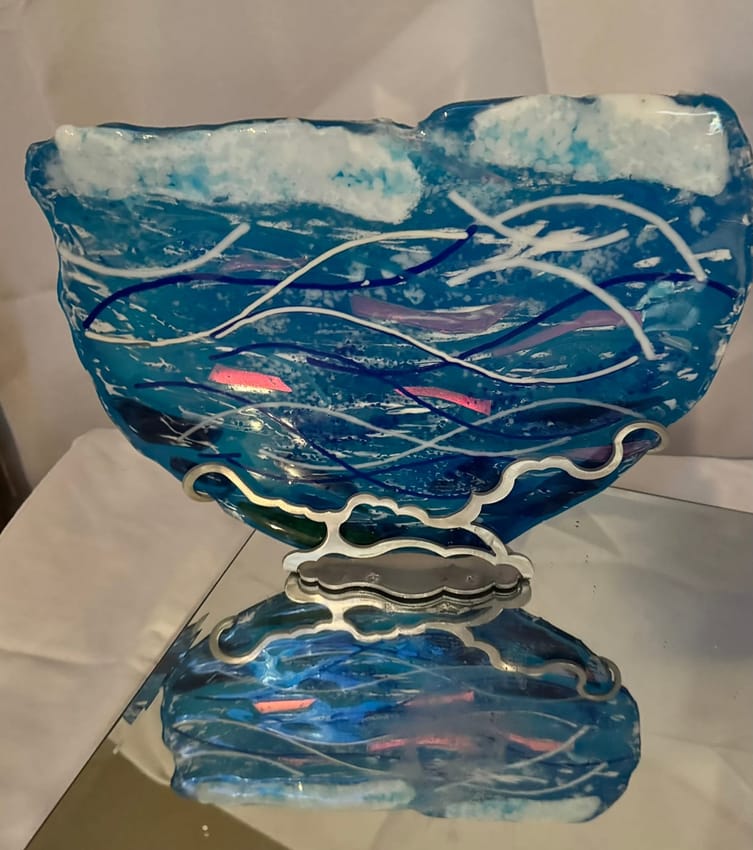 Wave-patterned glass bowl sculpture on a mirrored stand